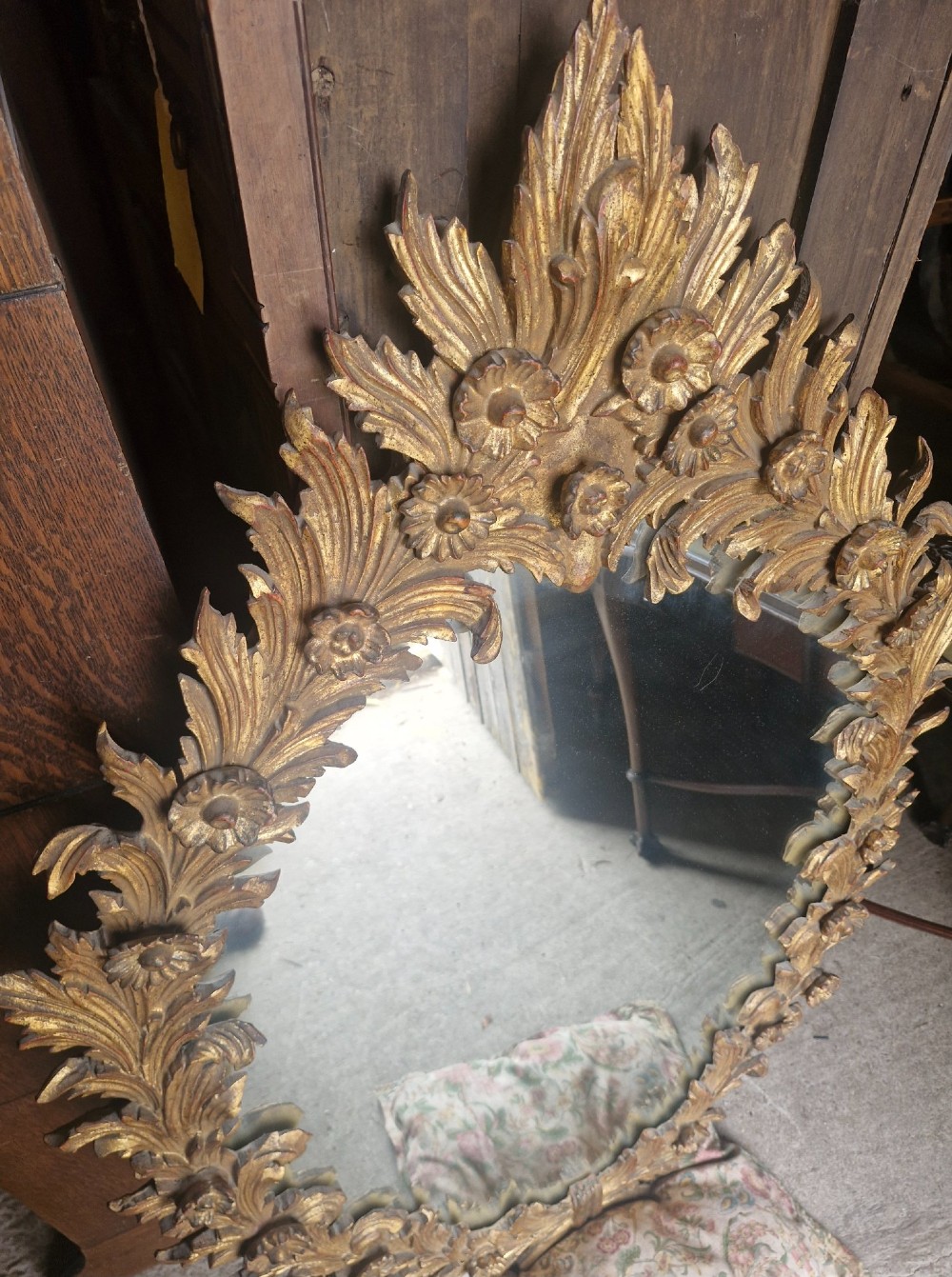An oval wall mirror featuring a carved giltwood frame decorated with detailed acanthus leaves and floral motifs. View IV
