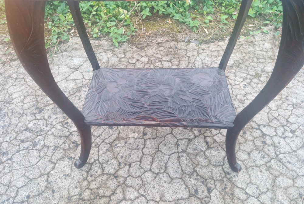 A dark brown two-tier wooden occasional table featuring intricate floral relief carvings across both flat surfaces and supported by four curved legs. View III