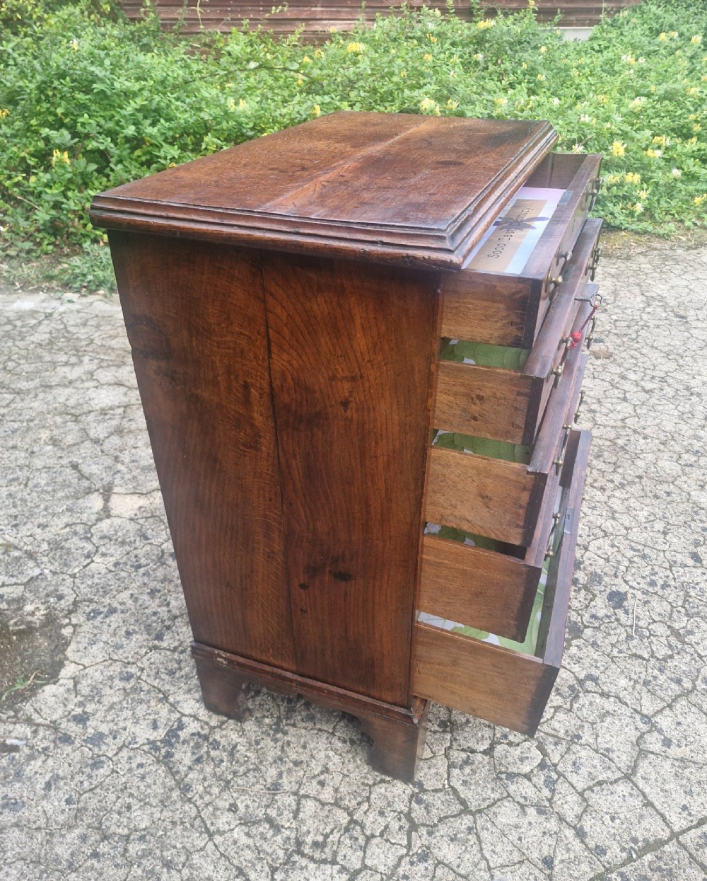 A Georgian oak chest of drawers featuring five graduated drawers with brass swan-neck handles and bracket feet. View VII