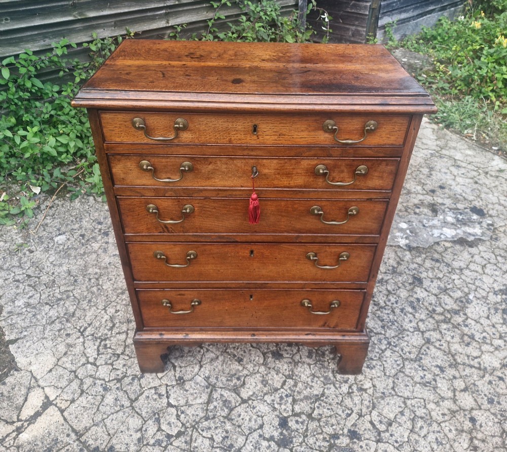 A Georgian oak chest of drawers featuring five graduated drawers with brass swan-neck handles and bracket feet. View VIII