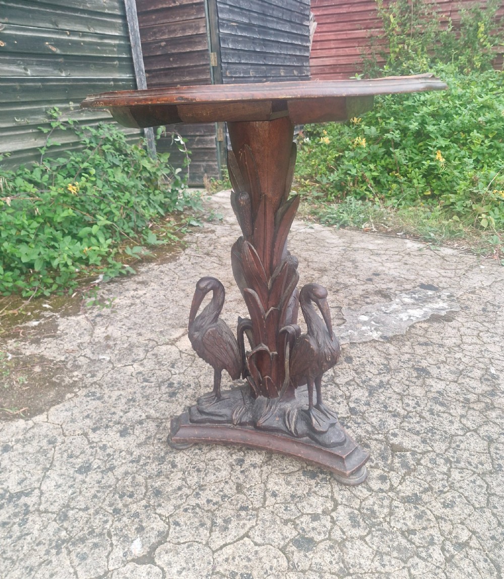 A Victorian carved oak occasional table featuring sculpted wading birds encircling a central pedestal above a triform base. View V