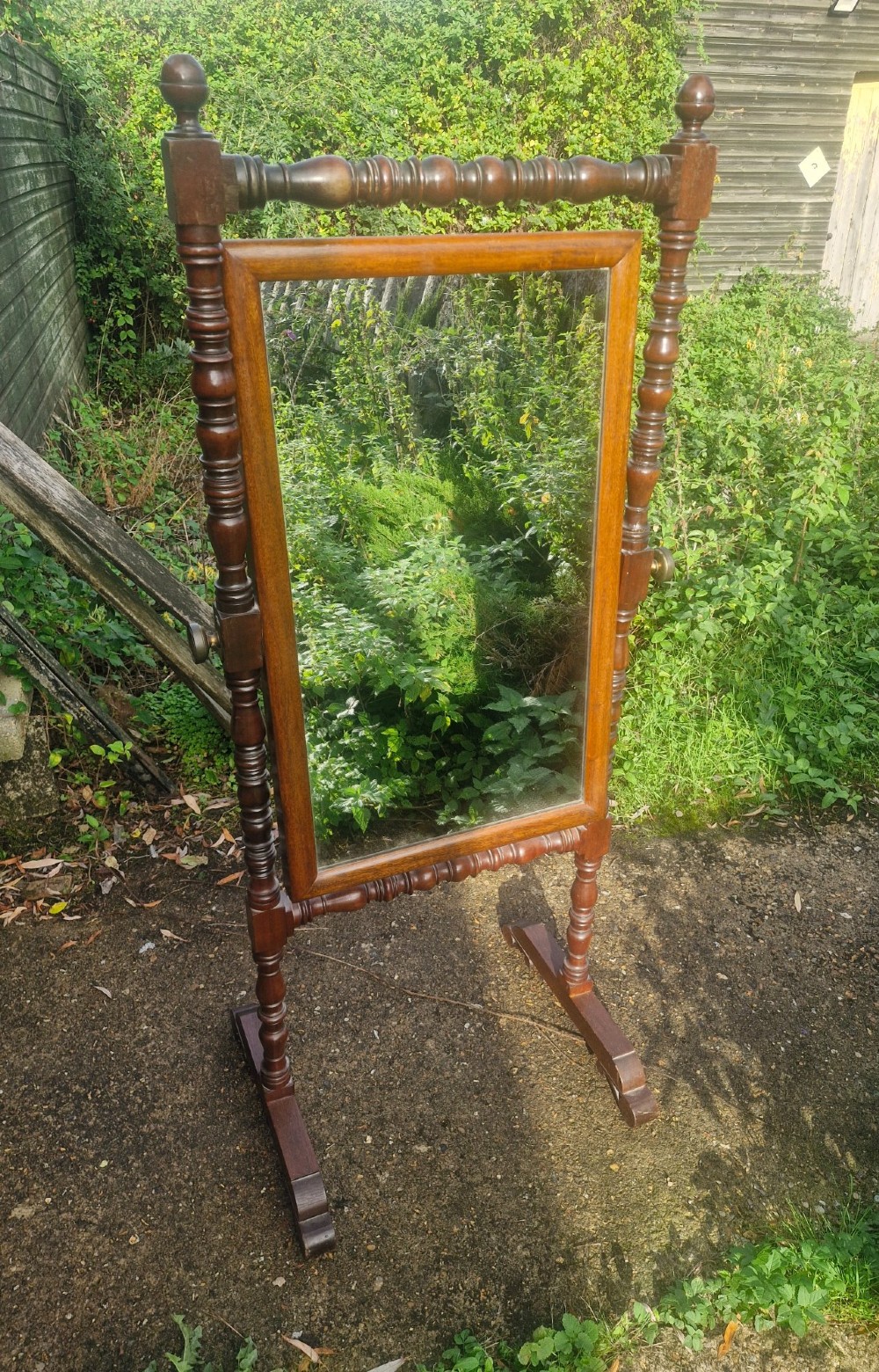A 19th-century dark mahogany cheval dressing mirror featuring turned upright supports, finials, a rectangular tilting glass, and splayed trestle feet. View III