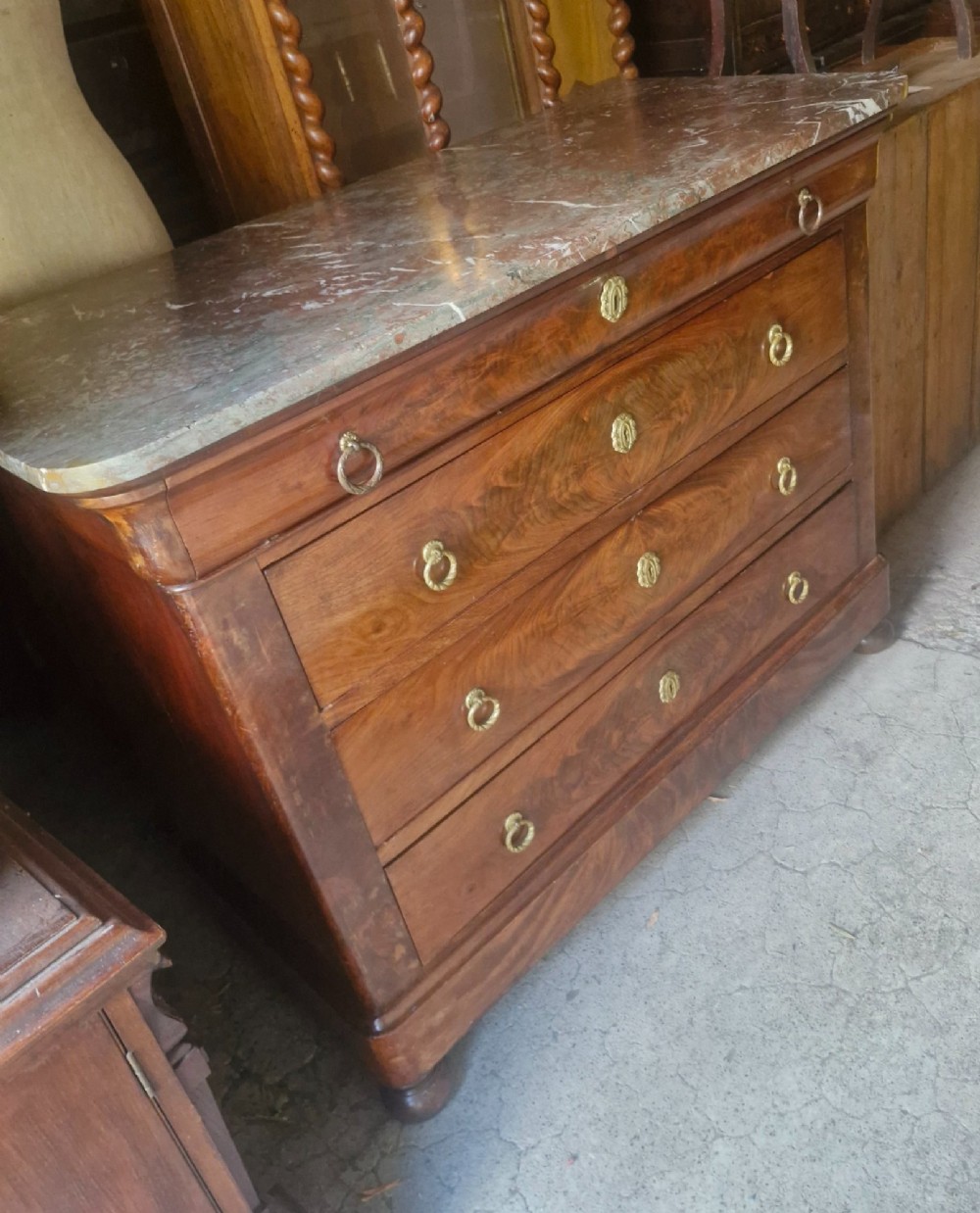 A nineteenth-century French mahogany chest of drawers featuring four drawers with brass ring pulls, escutcheons, and a grey veined marble top. View II