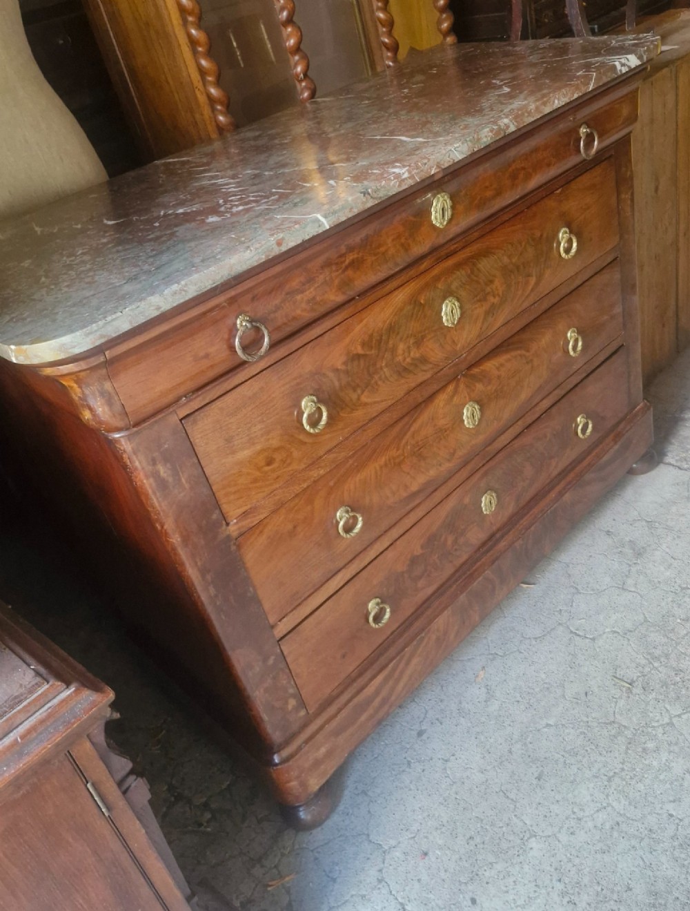 A nineteenth-century French mahogany chest of drawers featuring four drawers with brass ring pulls, escutcheons, and a grey veined marble top. View IV