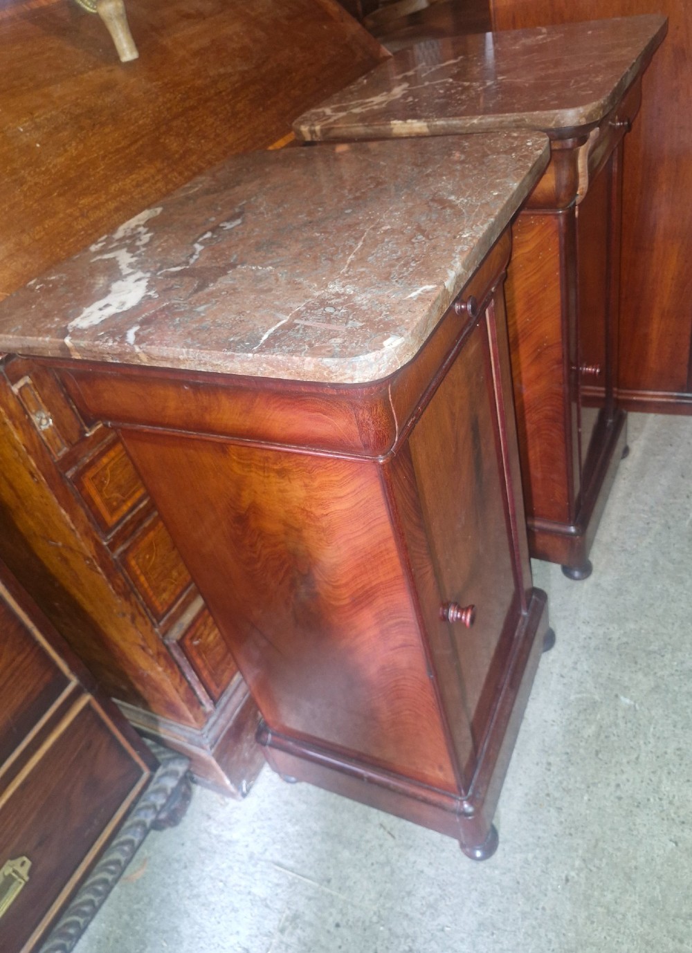 A pair of French mahogany bedside cabinets with reddish brown marble tops, upper drawers, and single panelled doors. View II
