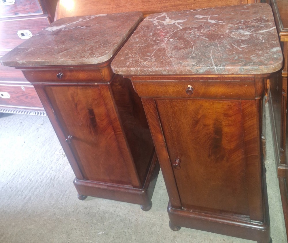 A pair of French mahogany bedside cabinets with reddish brown marble tops, upper drawers, and single panelled doors. View IV