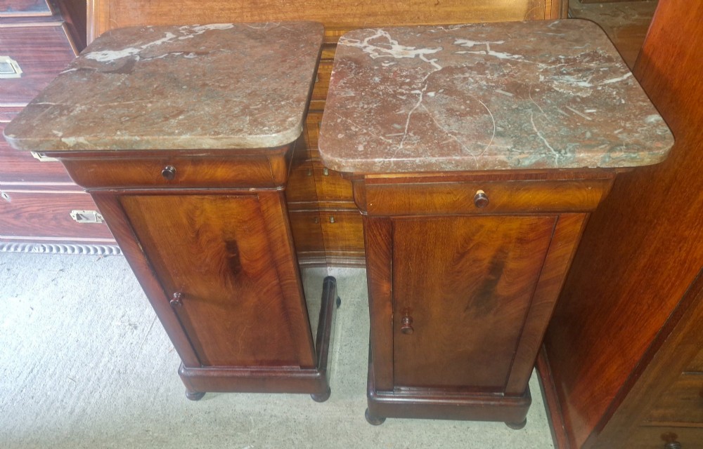 A pair of French mahogany bedside cabinets with reddish brown marble tops, upper drawers, and single panelled doors. View V