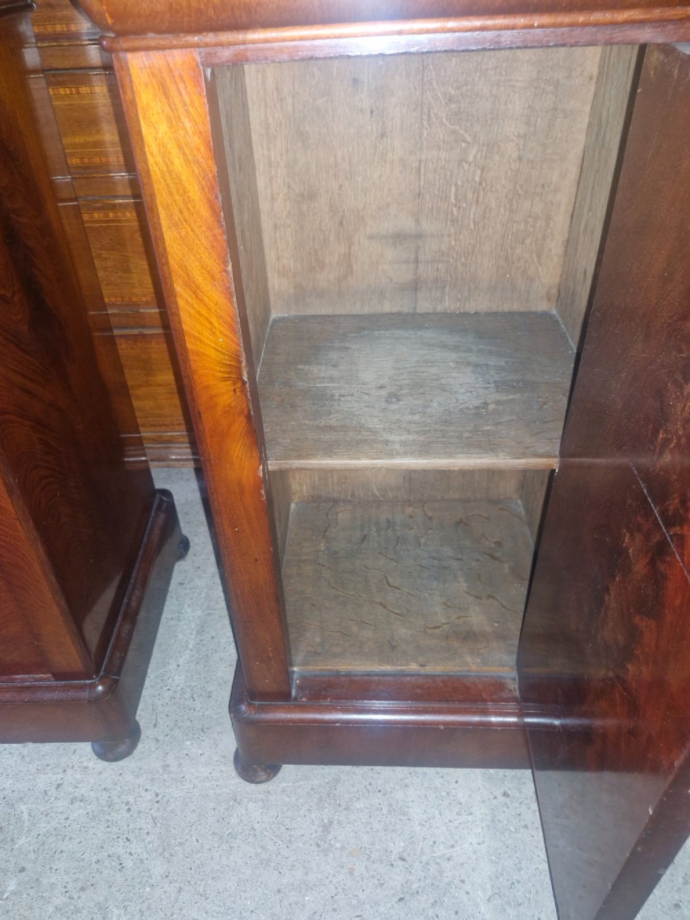 A pair of French mahogany bedside cabinets with reddish brown marble tops, upper drawers, and single panelled doors. View VI