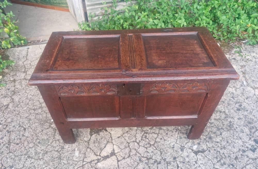 An 18th century dark oak coffer chest with carved arch motifs across the upper frieze, two front panels, and a central iron keyplate. View V