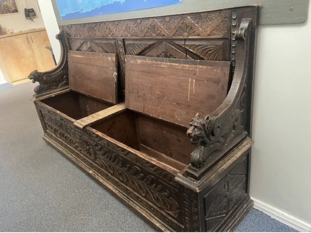 A large Victorian carved dark oak hall bench featuring a high panelled backrest with relief carving and carved lion mask armrests. View II