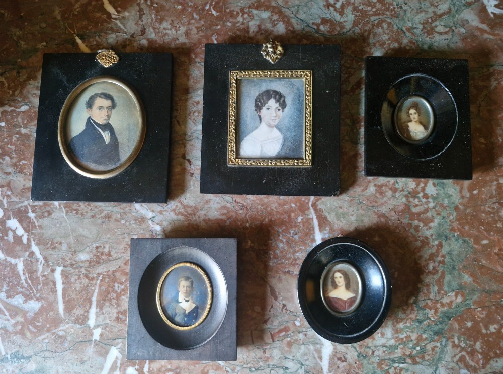 A set of five 19th-century antique portrait miniatures painted on papercard, displayed in dark ebonised frames with brass bezel rims.