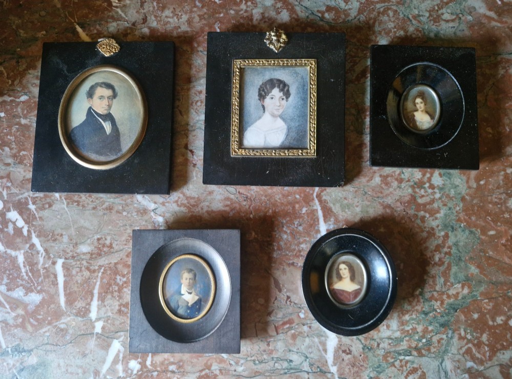 A set of five 19th-century antique portrait miniatures painted on papercard, displayed in dark ebonised frames with brass bezel rims. View II