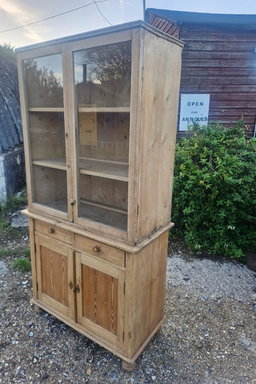 An antique two-part pine kitchen cupboard featuring an upper glazed cabinet with two shelves and a lower base with two drawers above panelled doors. View IV