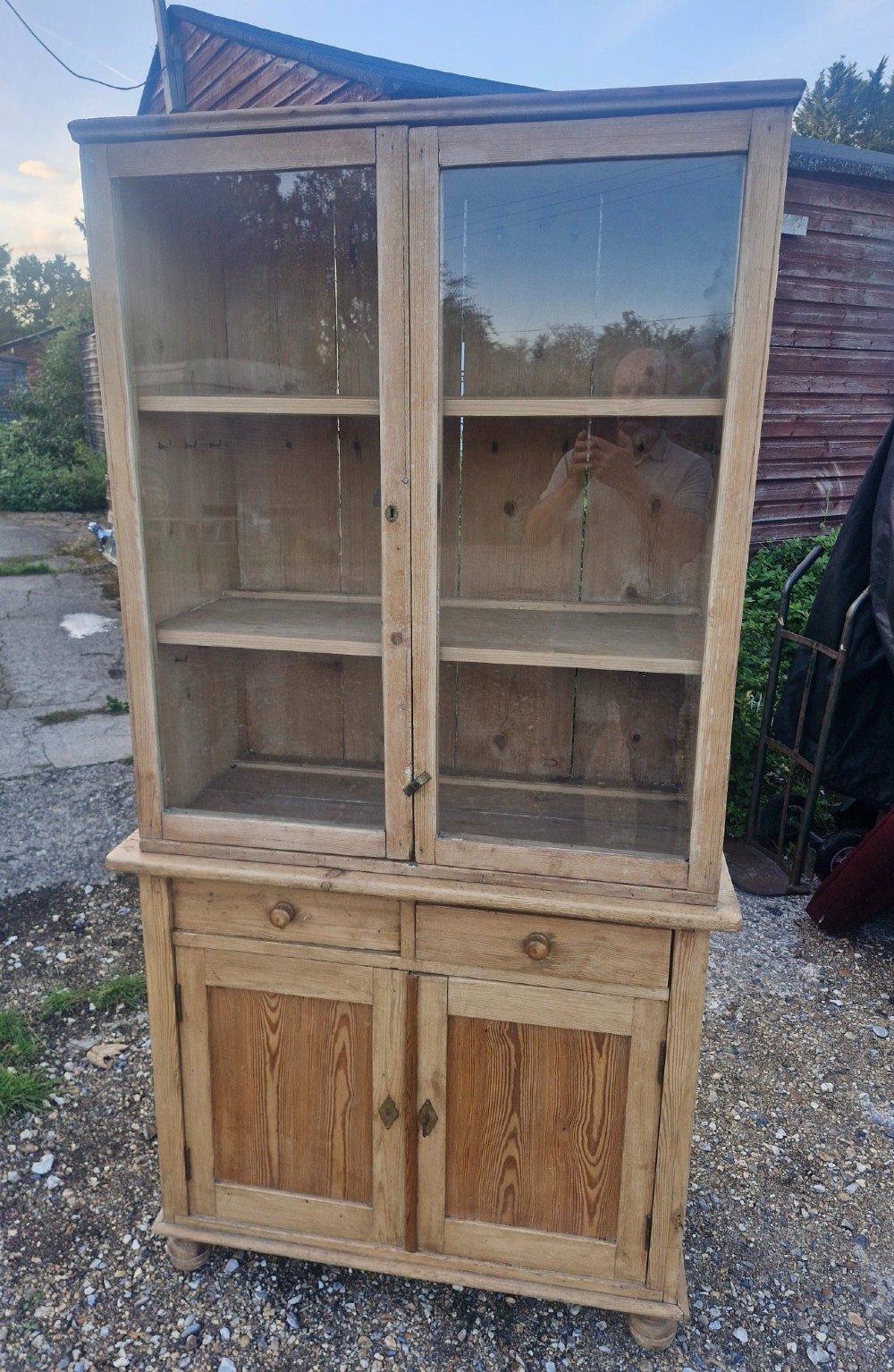 An antique two-part pine kitchen cupboard featuring an upper glazed cabinet with two shelves and a lower base with two drawers above panelled doors. View V