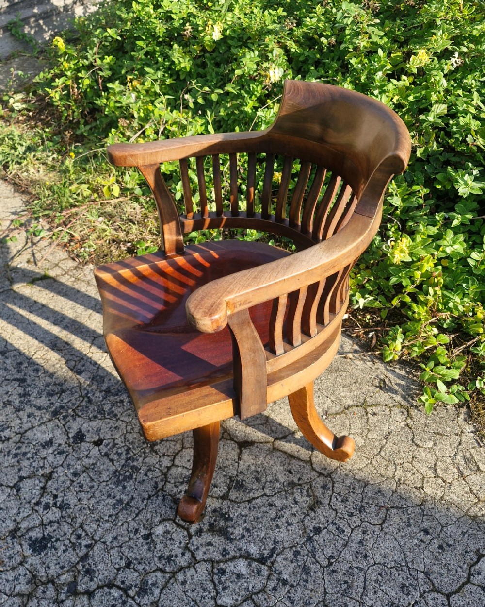 A solid mahogany revolving desk armchair featuring a curved spindle backrest, shaped seat, and splayed legs. View II