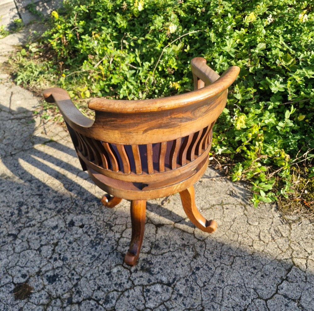 A solid mahogany revolving desk armchair featuring a curved spindle backrest, shaped seat, and splayed legs. View III