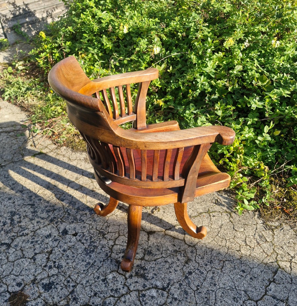 A solid mahogany revolving desk armchair featuring a curved spindle backrest, shaped seat, and splayed legs. View IV