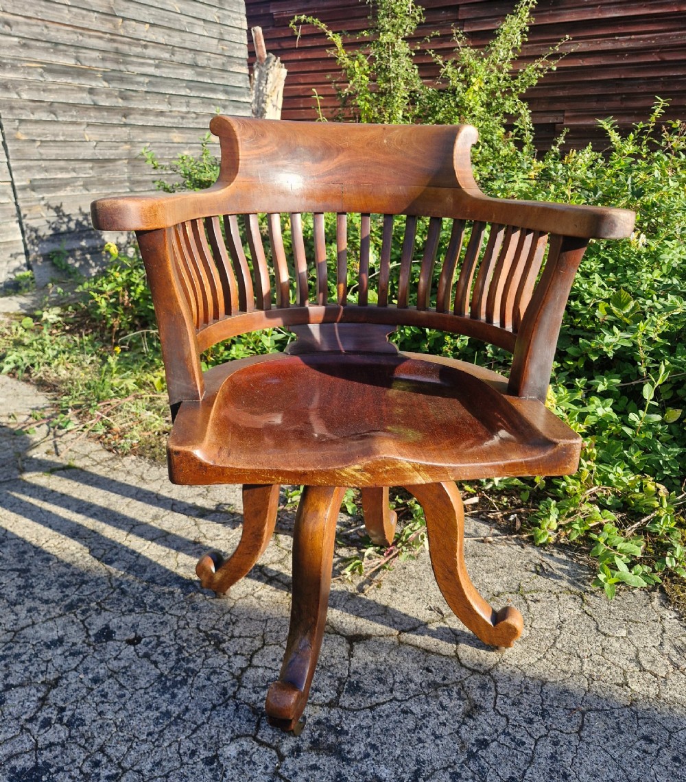 A solid mahogany revolving desk armchair featuring a curved spindle backrest, shaped seat, and splayed legs. View VI