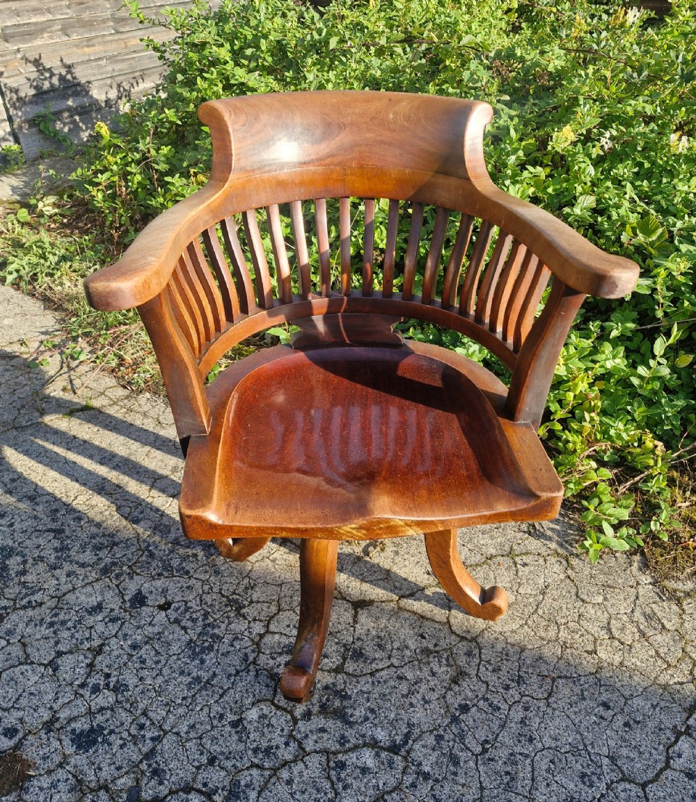 A solid mahogany revolving desk armchair featuring a curved spindle backrest, shaped seat, and splayed legs. View VII