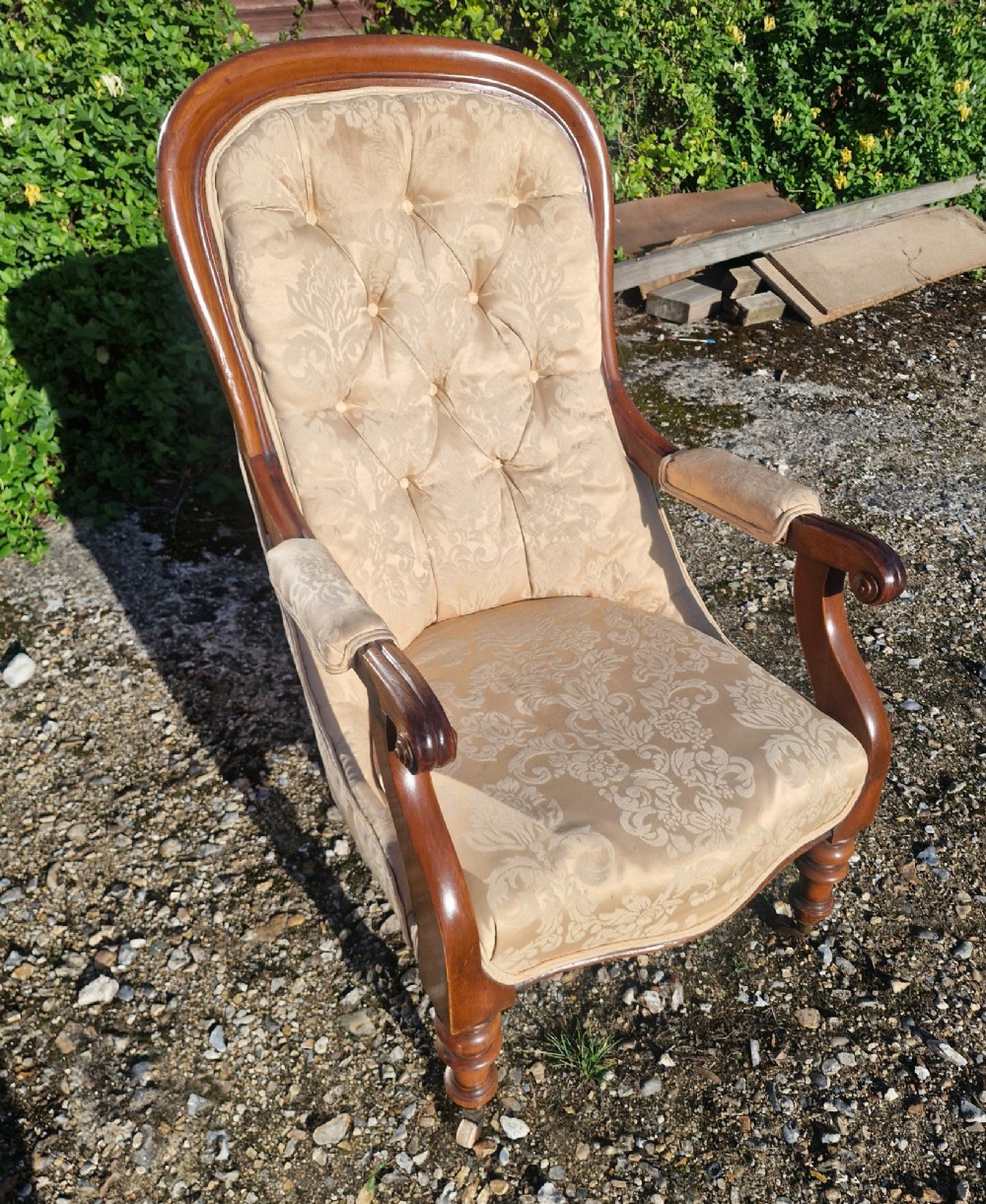 Victorian mahogany library armchair upholstered in gold damask fabric featuring a button-tufted back, scrolled armrests, and turned legs with brass castors. View III