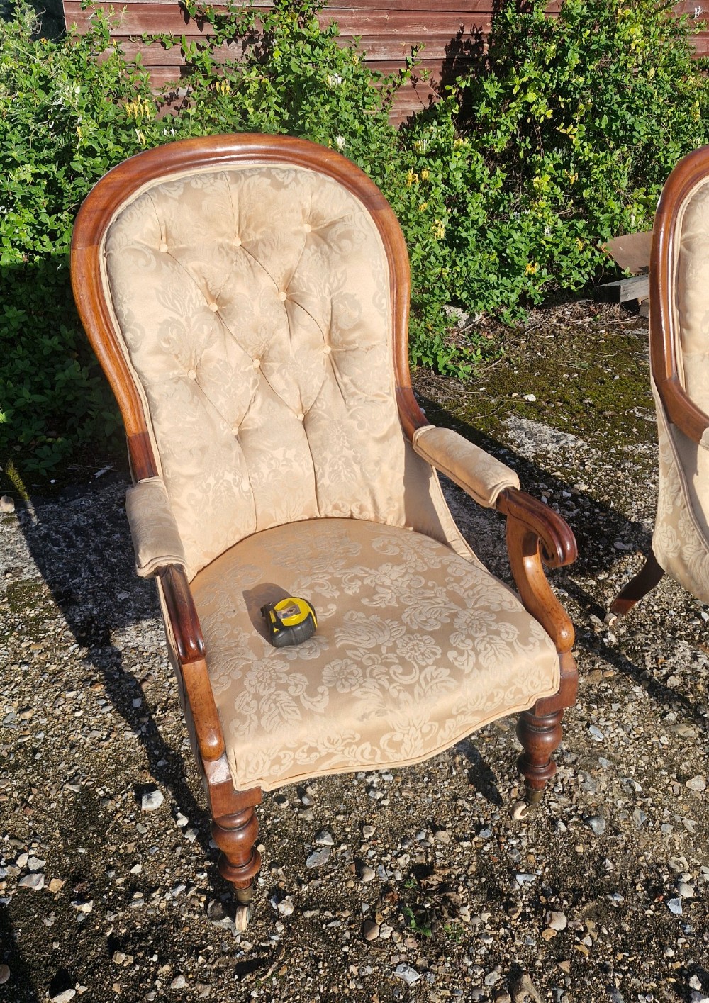 Victorian mahogany library armchair upholstered in gold damask fabric featuring a button-tufted back, scrolled armrests, and turned legs with brass castors. View VI