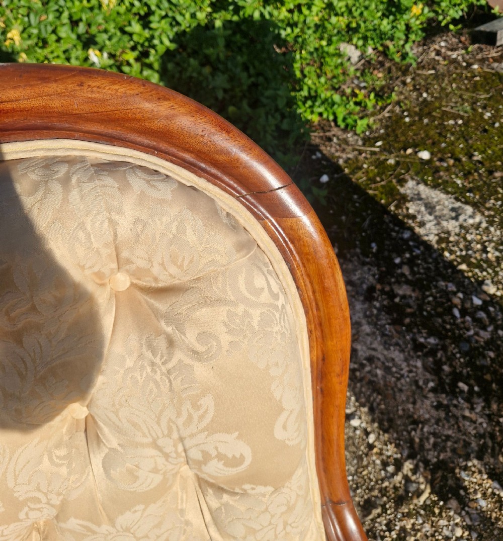 Victorian mahogany library armchair upholstered in gold damask fabric featuring a button-tufted back, scrolled armrests, and turned legs with brass castors. View IX