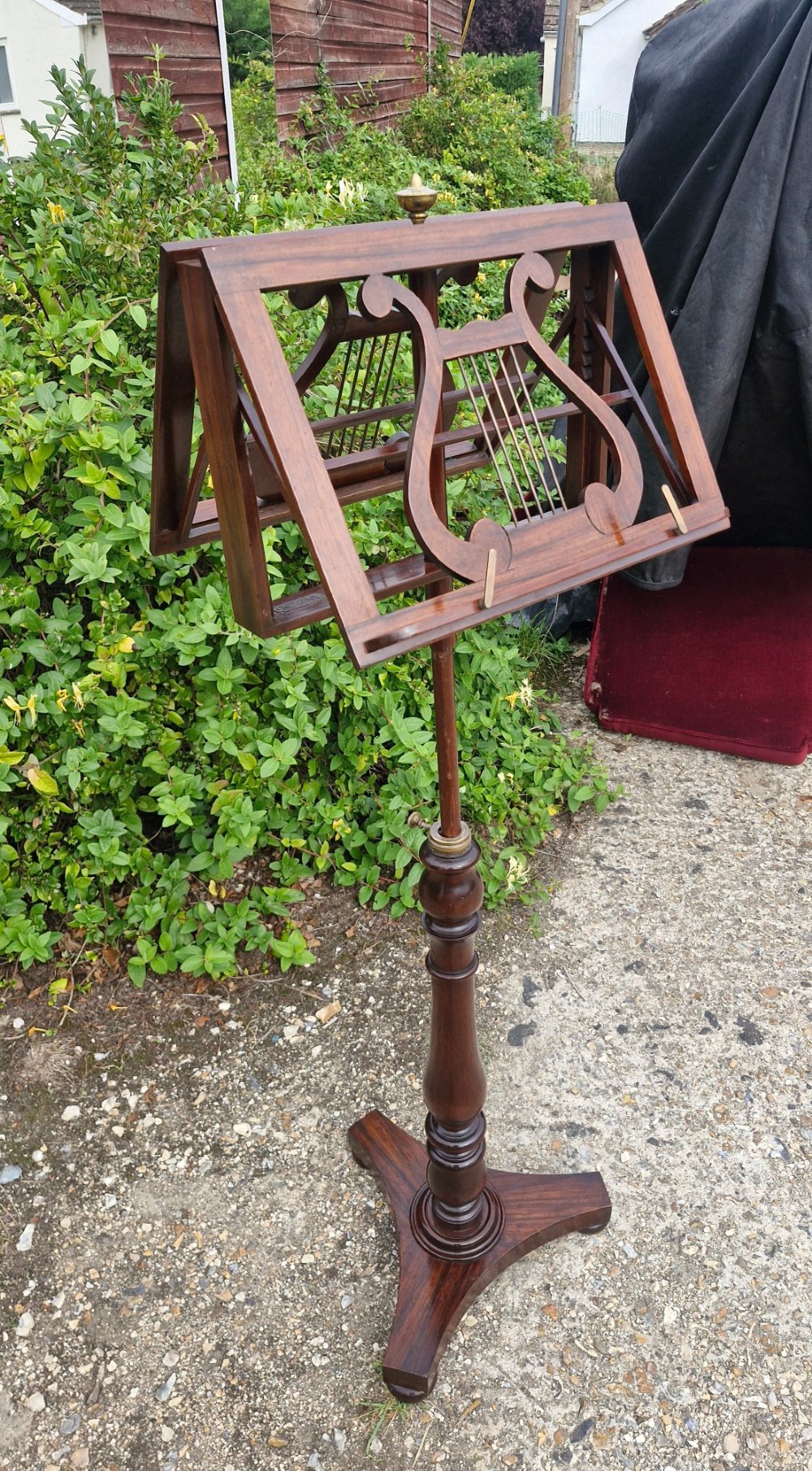 An early Victorian double-sided dark wood duet music stand featuring lyre-shaped rests and a turned pedestal column on a triform base. View V