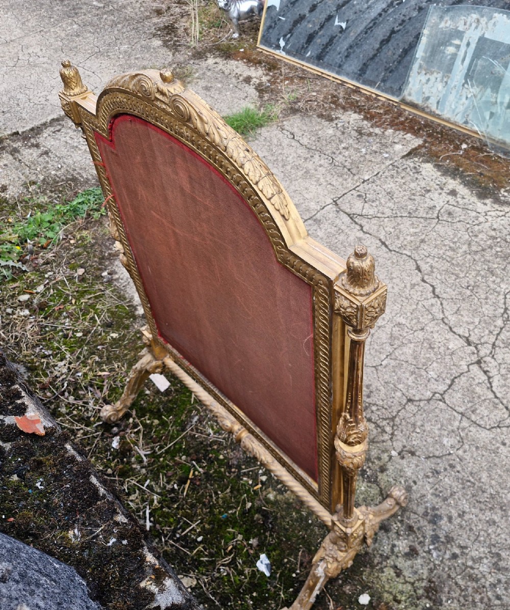 A Victorian carved giltwood fire screen featuring an arched frame, turned side columns, scroll feet, and a central tapestry panel depicting figures in traditional rural attire. View II