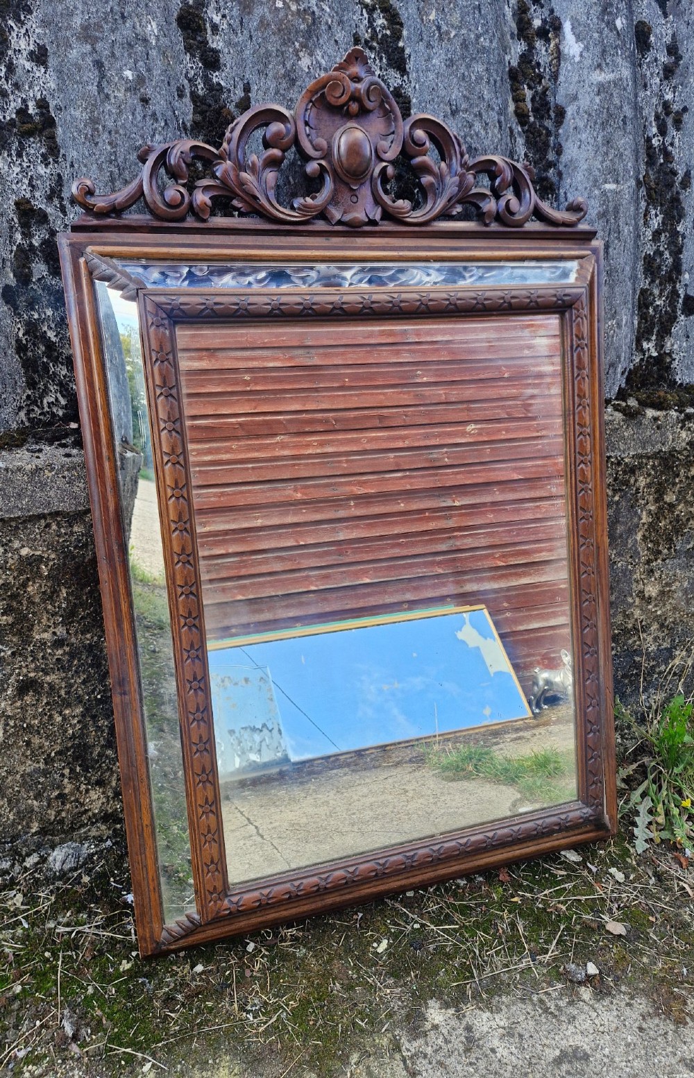 A rectangular French oak wall mirror featuring a bevelled glass plate and a pierced carved cresting with scroll motifs.