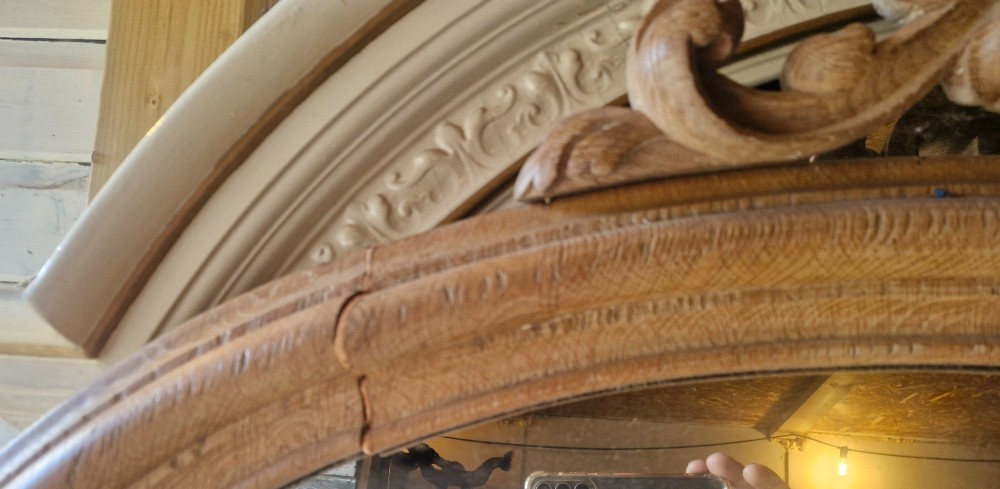 A large 19th-century arched oak wall mirror featuring an intricate carved scrollwork crest and a molded frame. View VII