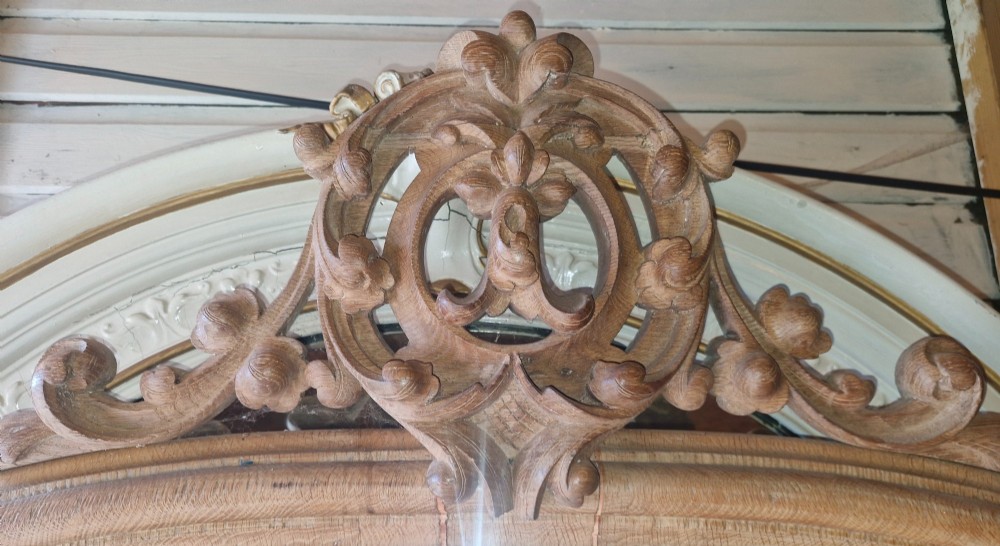 A large 19th-century arched oak wall mirror featuring an intricate carved scrollwork crest and a molded frame. View IX