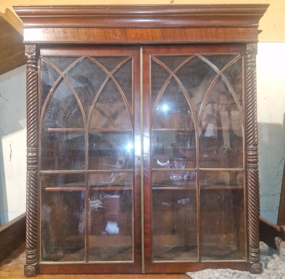 A Regency mahogany wall cabinet featuring two Gothic astragal glazed doors, spiral-turned side columns, and carved roundel corner details. View II