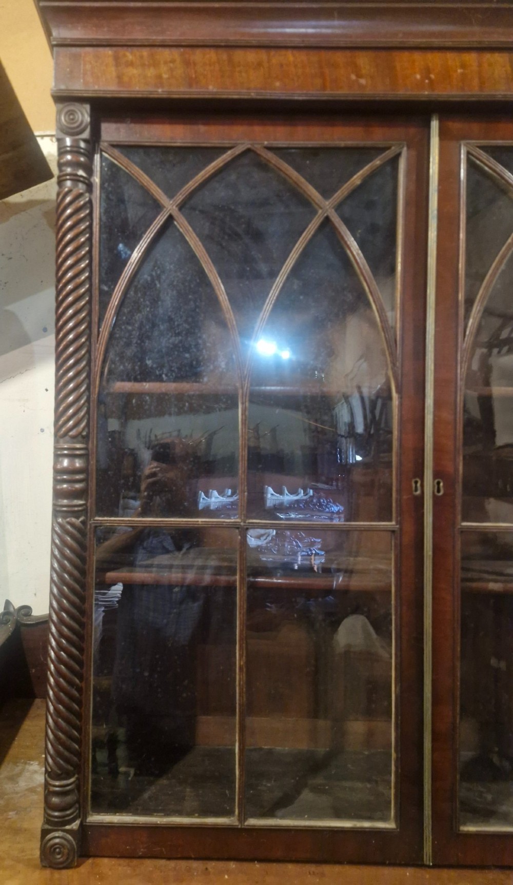 A Regency mahogany wall cabinet featuring two Gothic astragal glazed doors, spiral-turned side columns, and carved roundel corner details. View IV