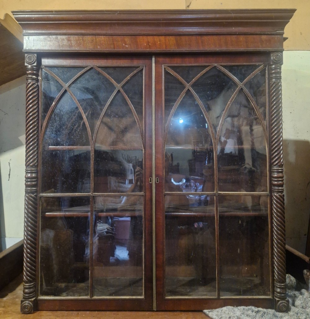 A Regency mahogany wall cabinet featuring two Gothic astragal glazed doors, spiral-turned side columns, and carved roundel corner details. View V