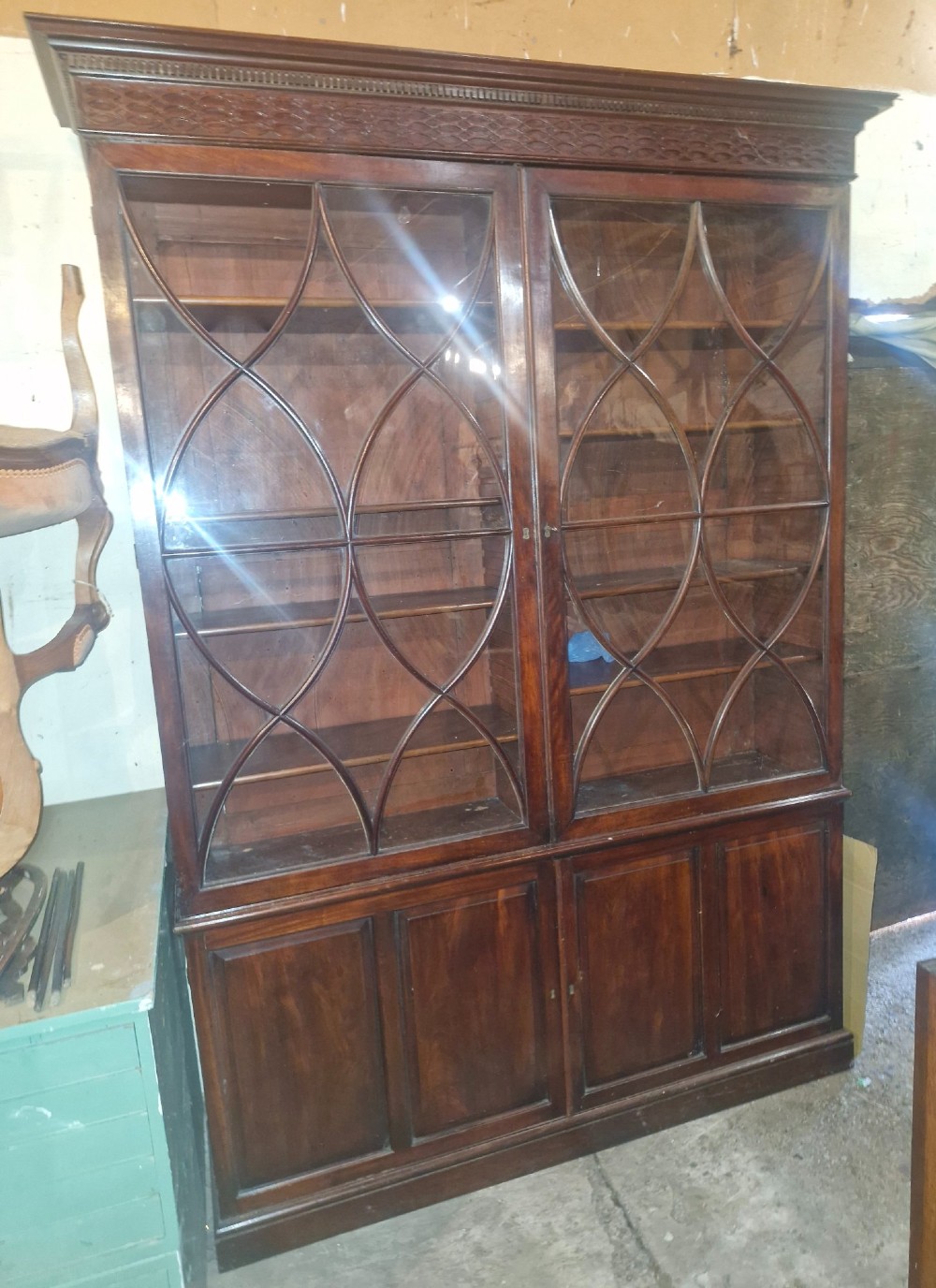 An early 19th-century mahogany library bookcase with double upper glazed doors featuring curved geometric glazing bars over a panelled two-door base.