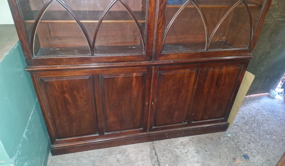 An early 19th-century mahogany library bookcase with double upper glazed doors featuring curved geometric glazing bars over a panelled two-door base. View V
