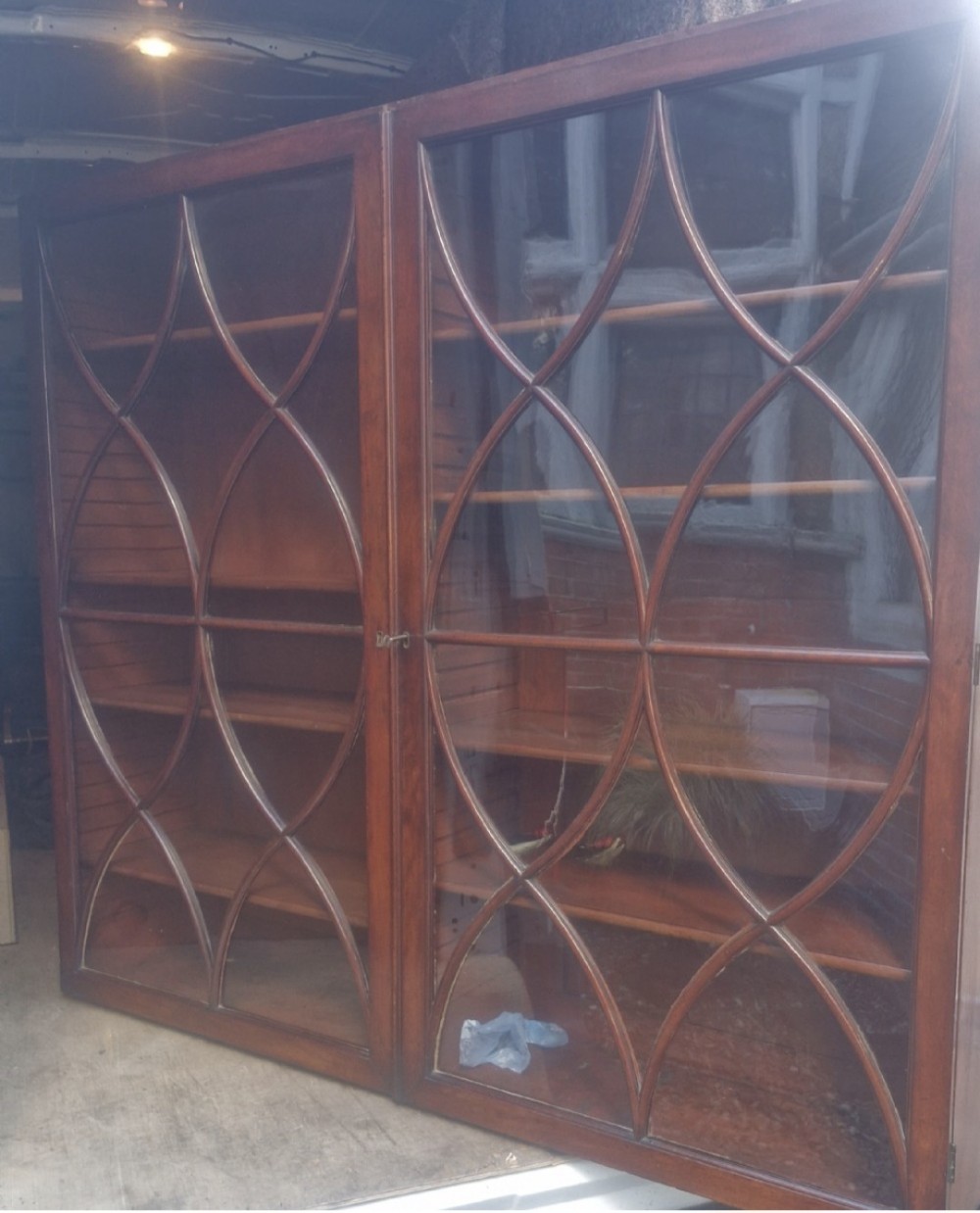 An early 19th-century mahogany library bookcase with double upper glazed doors featuring curved geometric glazing bars over a panelled two-door base. View VI