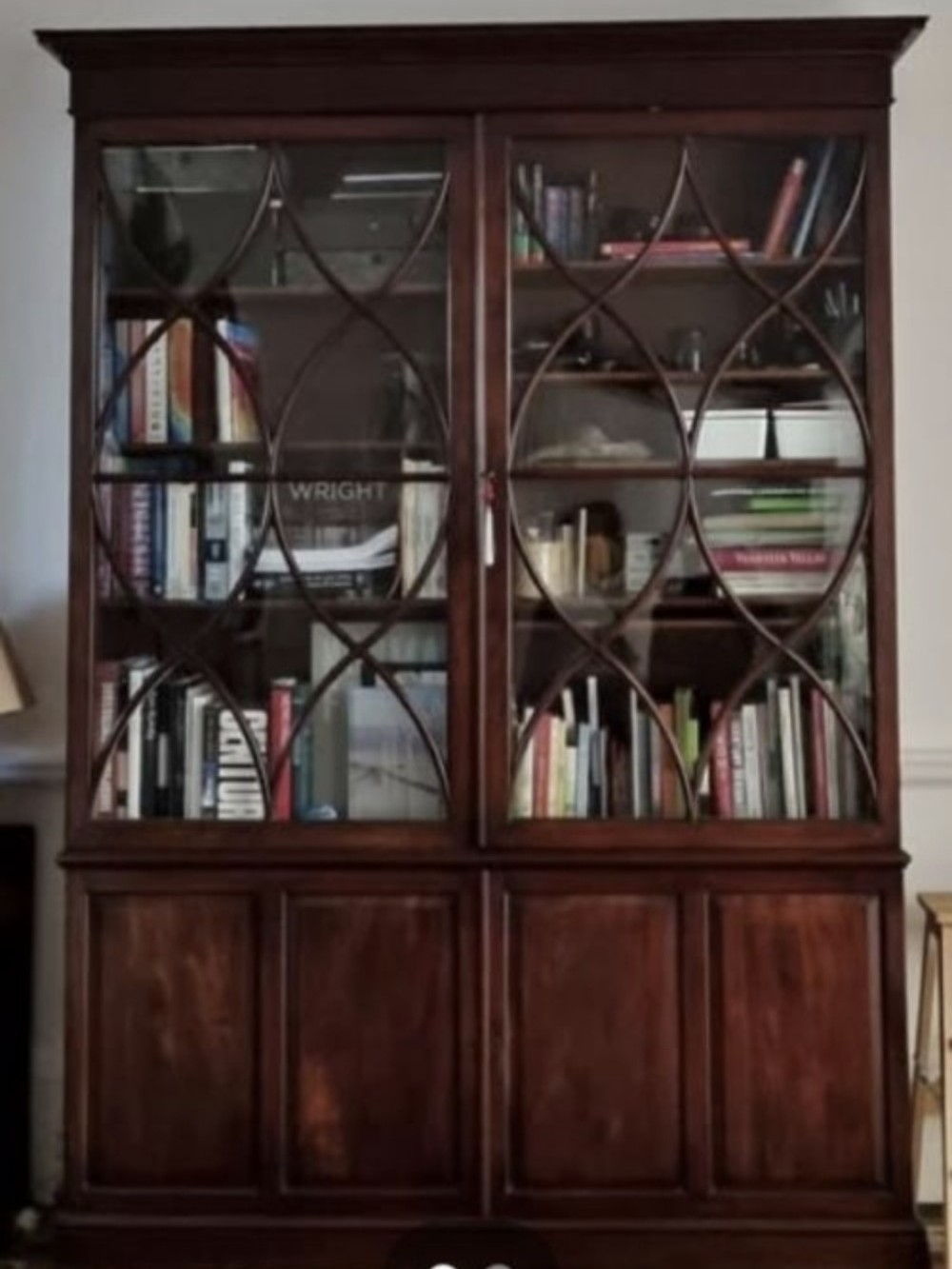An early 19th-century mahogany library bookcase with double upper glazed doors featuring curved geometric glazing bars over a panelled two-door base. View VII