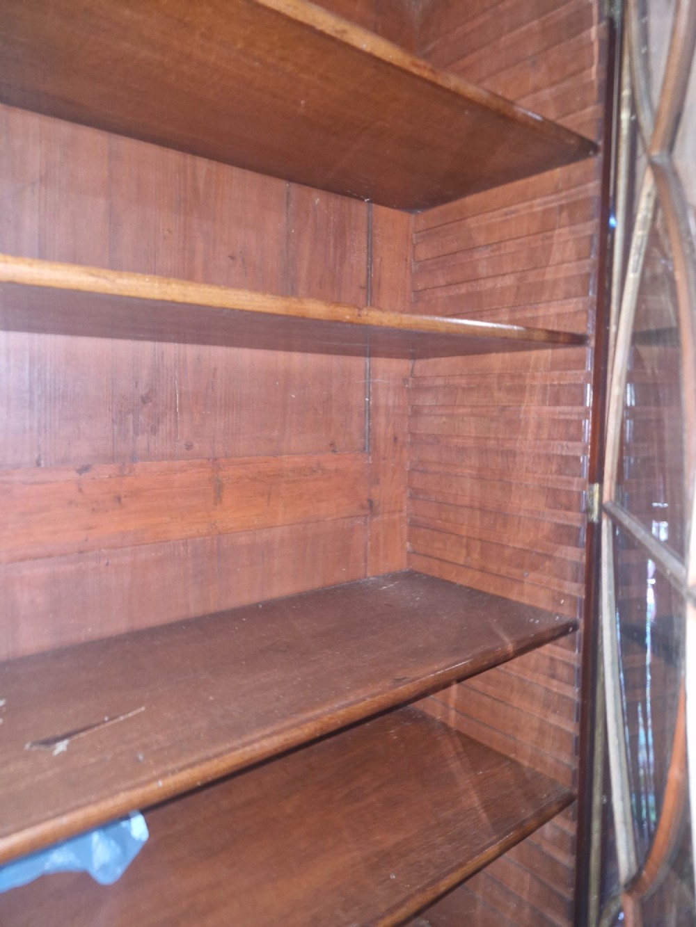 An early 19th-century mahogany library bookcase with double upper glazed doors featuring curved geometric glazing bars over a panelled two-door base. View VIII