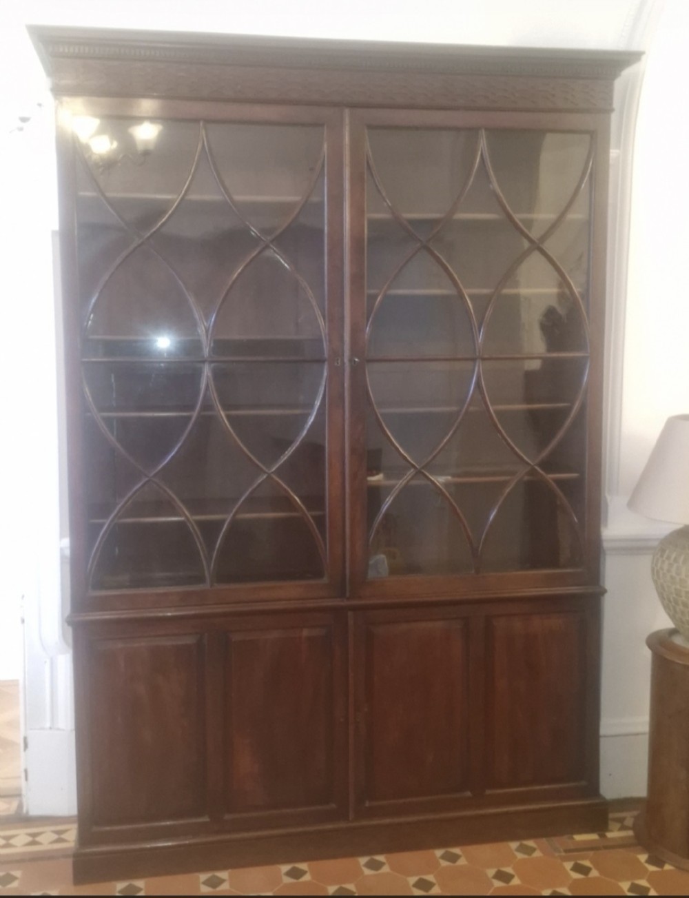 An early 19th-century mahogany library bookcase with double upper glazed doors featuring curved geometric glazing bars over a panelled two-door base. View IX