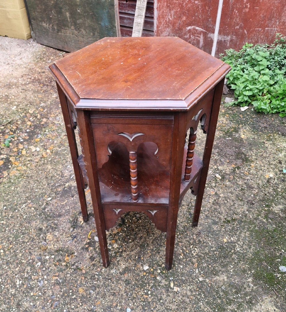 A dark mahogany hexagonal occasional table featuring a lower shelf, turned spindle supports, and cut-out decorative aprons. View VI