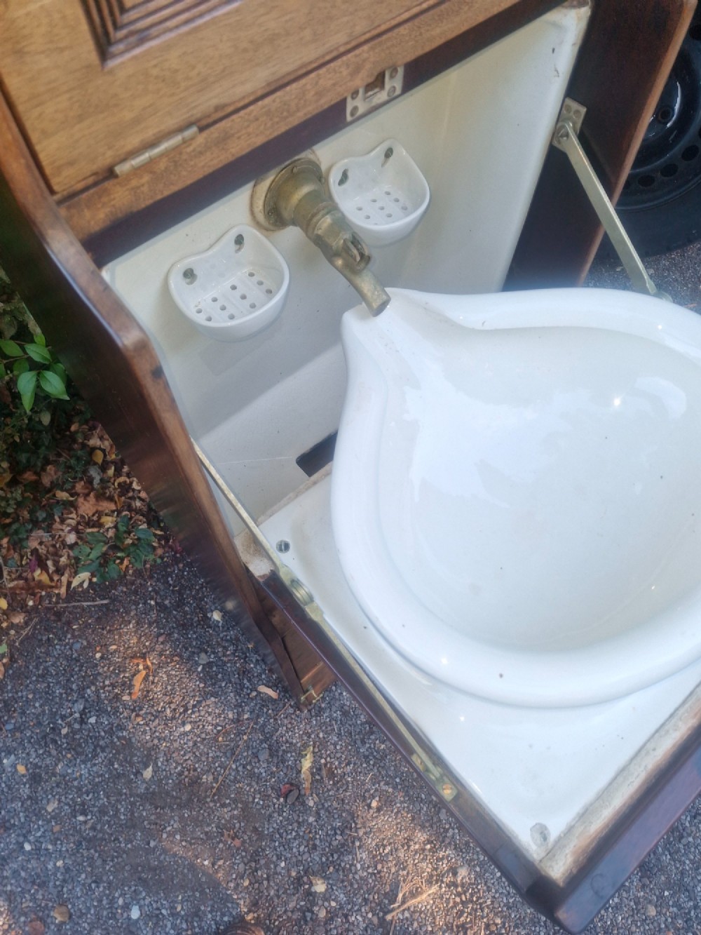 An Edwardian wooden ships washstand featuring an upper arched mirror, a middle drop-front door revealing a white ceramic washbasin, and lower cupboard doors. View V