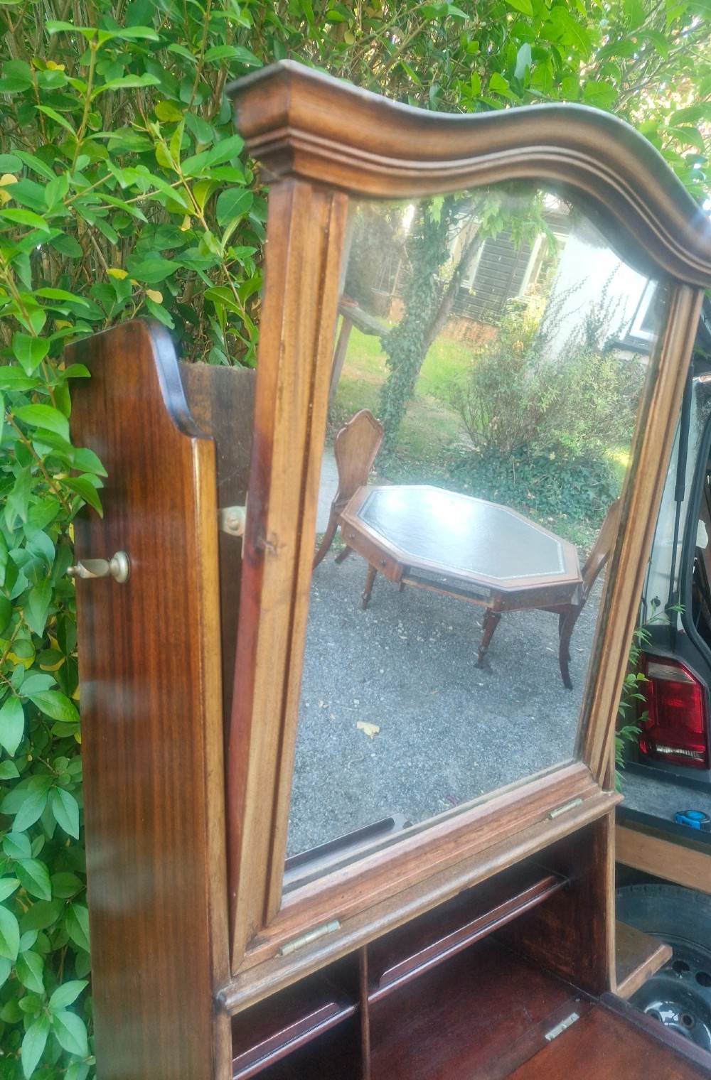 An Edwardian wooden ships washstand featuring an upper arched mirror, a middle drop-front door revealing a white ceramic washbasin, and lower cupboard doors. View VI