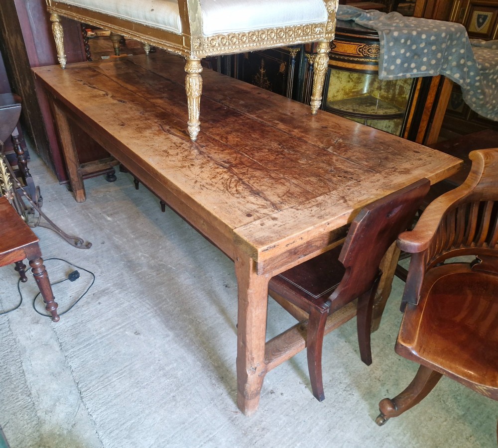 A rustic French farmhouse dining table made of weathered oak with a heavy plank top and sturdy stretcher base. View X