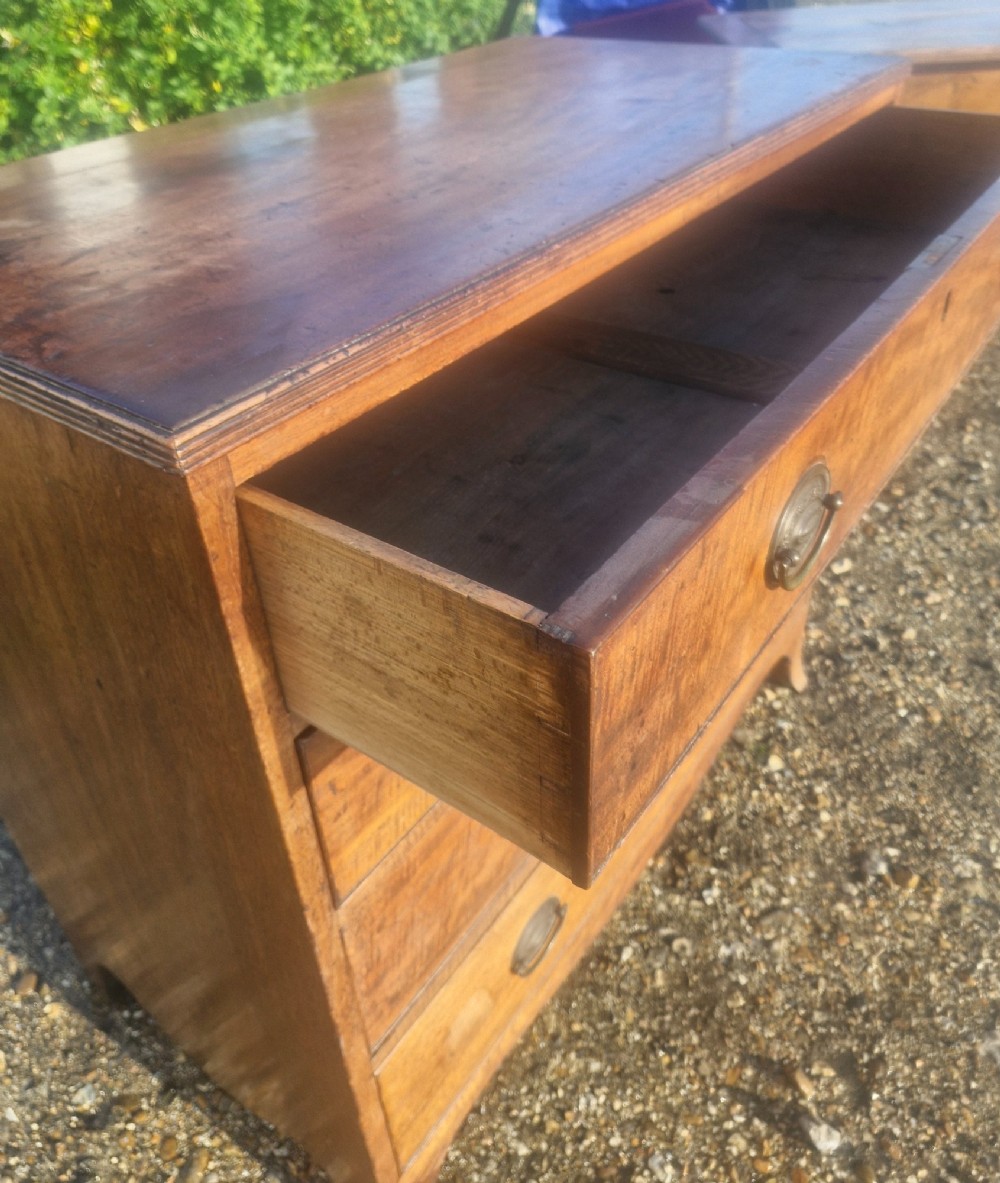 A Regency period mahogany chest of drawers with four graduated drawers, brass oval handles, and splayed bracket feet. View II