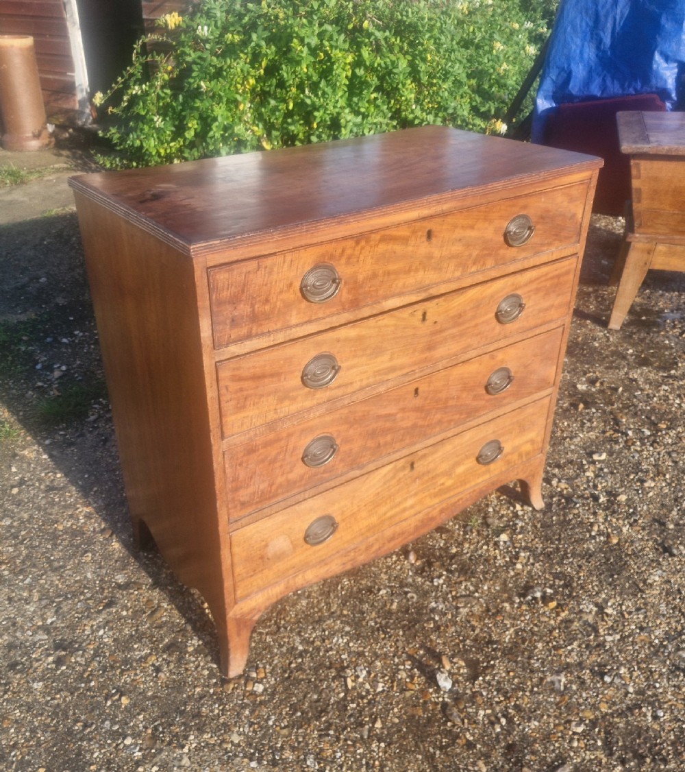 A Regency period mahogany chest of drawers with four graduated drawers, brass oval handles, and splayed bracket feet. View VI