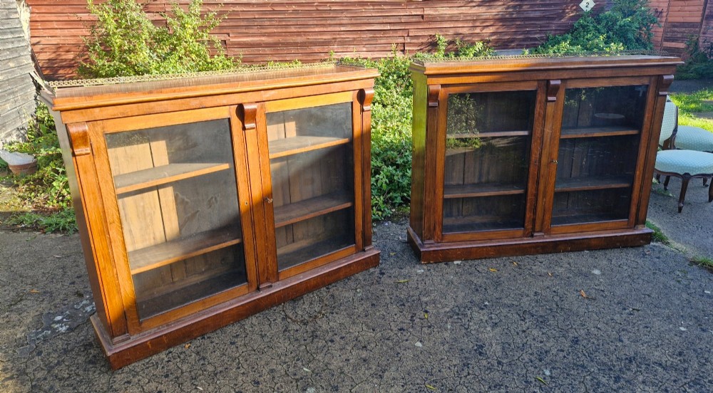 A pair of Victorian low oak bookcases featuring glazed twin doors, brass top gallery rails, carved corbels, and adjustable interior shelving. View XII