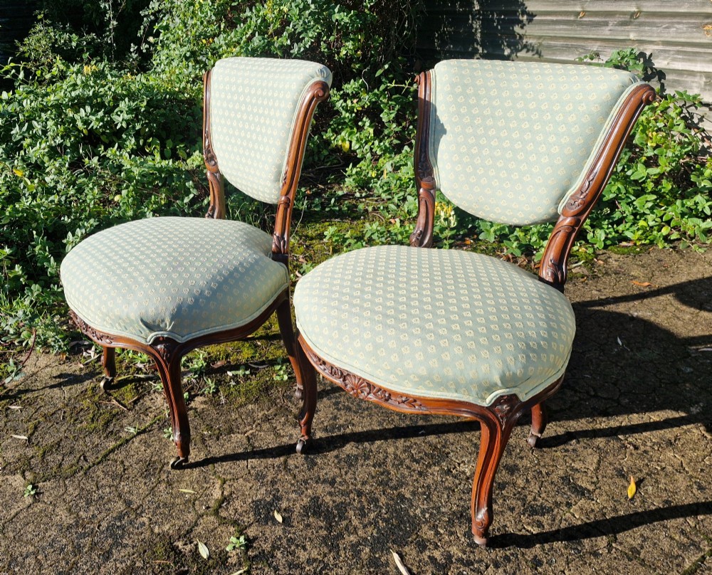 A pair of late Victorian walnut frame bedroom chairs with light green patterned upholstery and carved cabriole legs on brass castors. View III