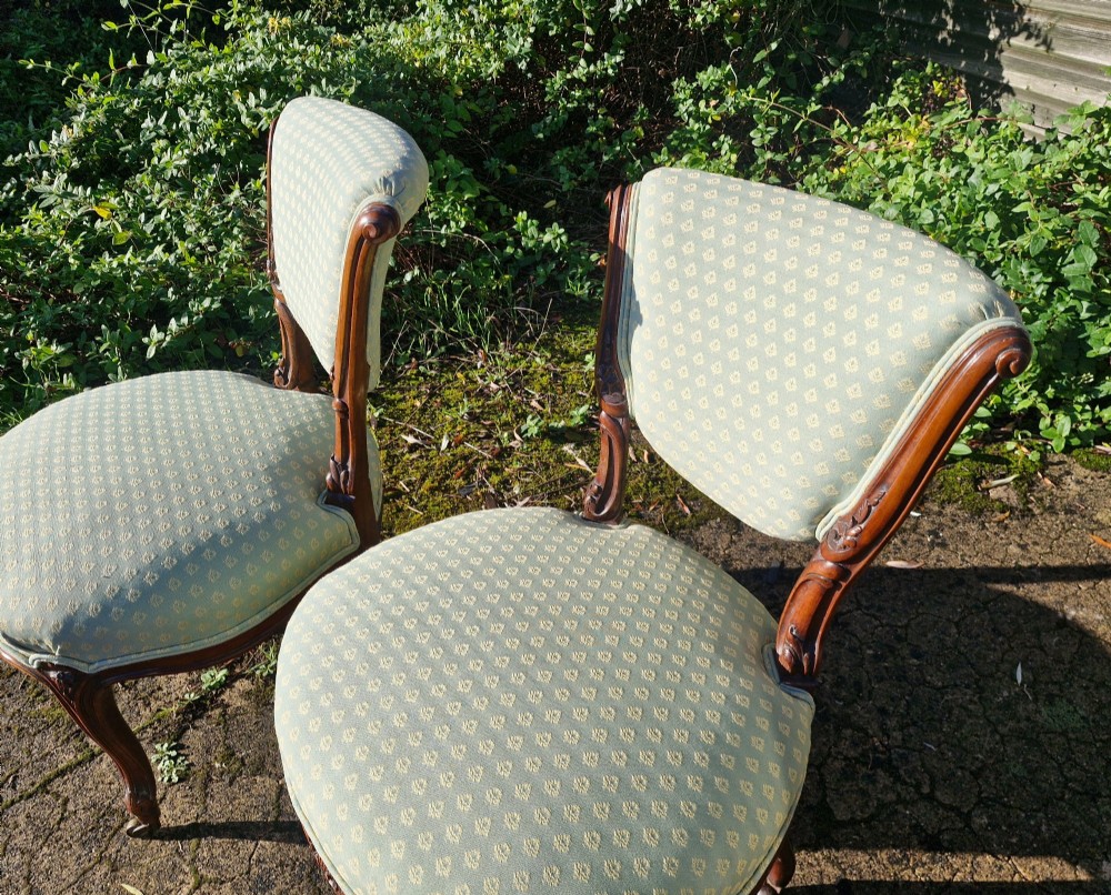A pair of late Victorian walnut frame bedroom chairs with light green patterned upholstery and carved cabriole legs on brass castors. View IV