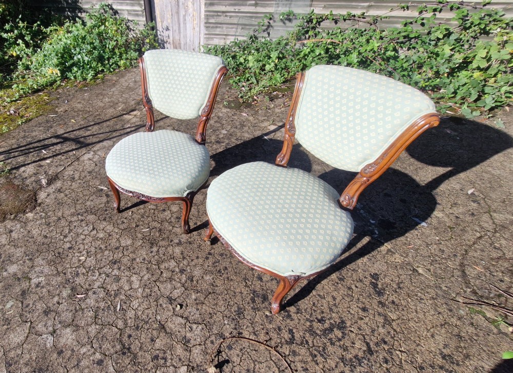 A pair of late Victorian low-seated bedroom chairs with carved walnut frames and light green patterned upholstery. View II